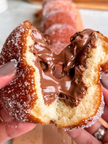 Donut being torn into two, with nutella oozing out from the center