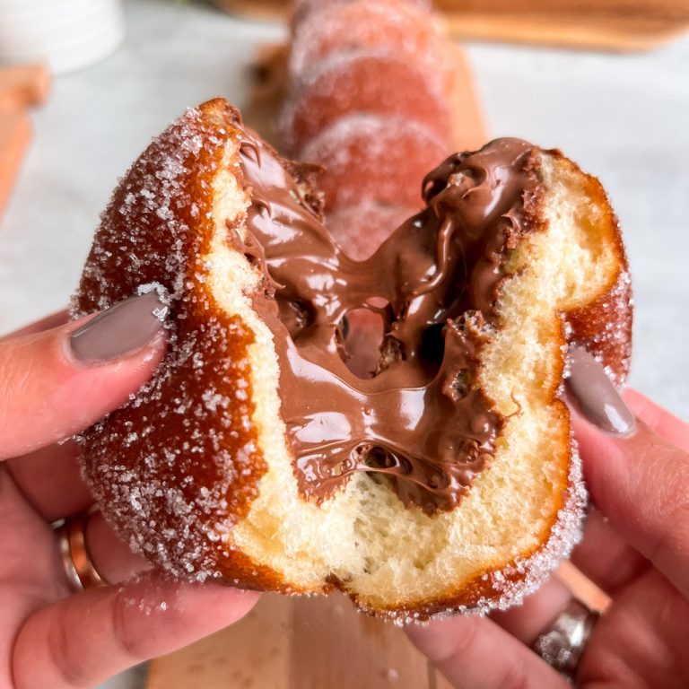 Donut being torn into two, with nutella oozing out from the center