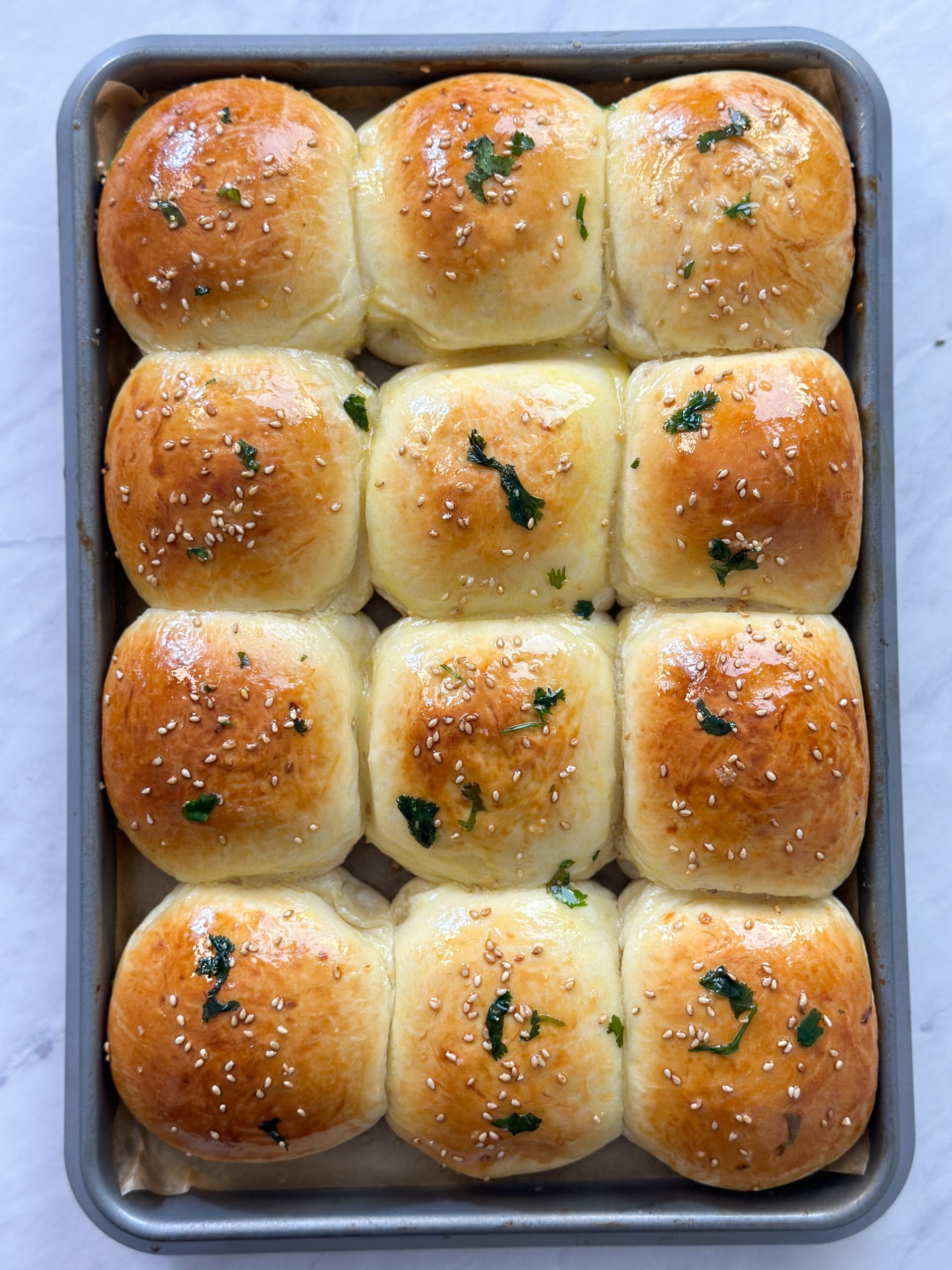 baked naan buns in a tray brushed with garlic butter and cilantro