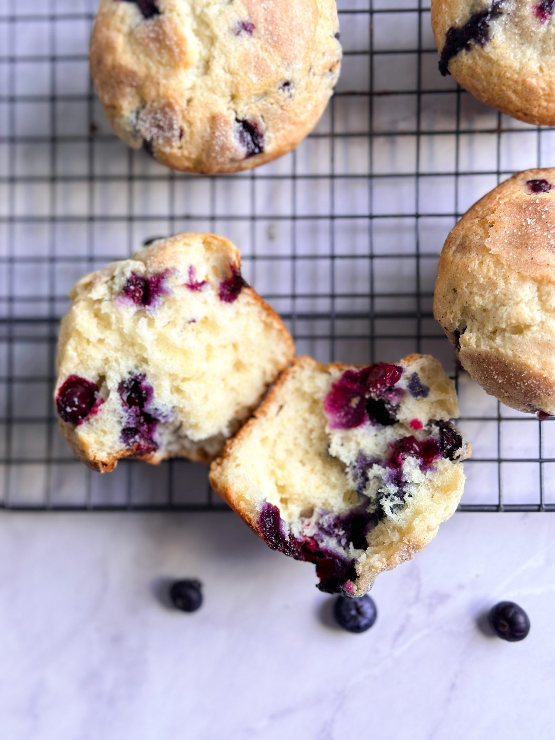 Close up of a lemon blueberry muffin sliced into 2 halves revealing soft fluffy interior with bursting blueberries