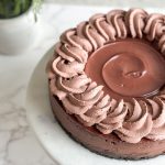 close up image of a chocolate cheesecake with ganache and chocolate whipped cream frosting