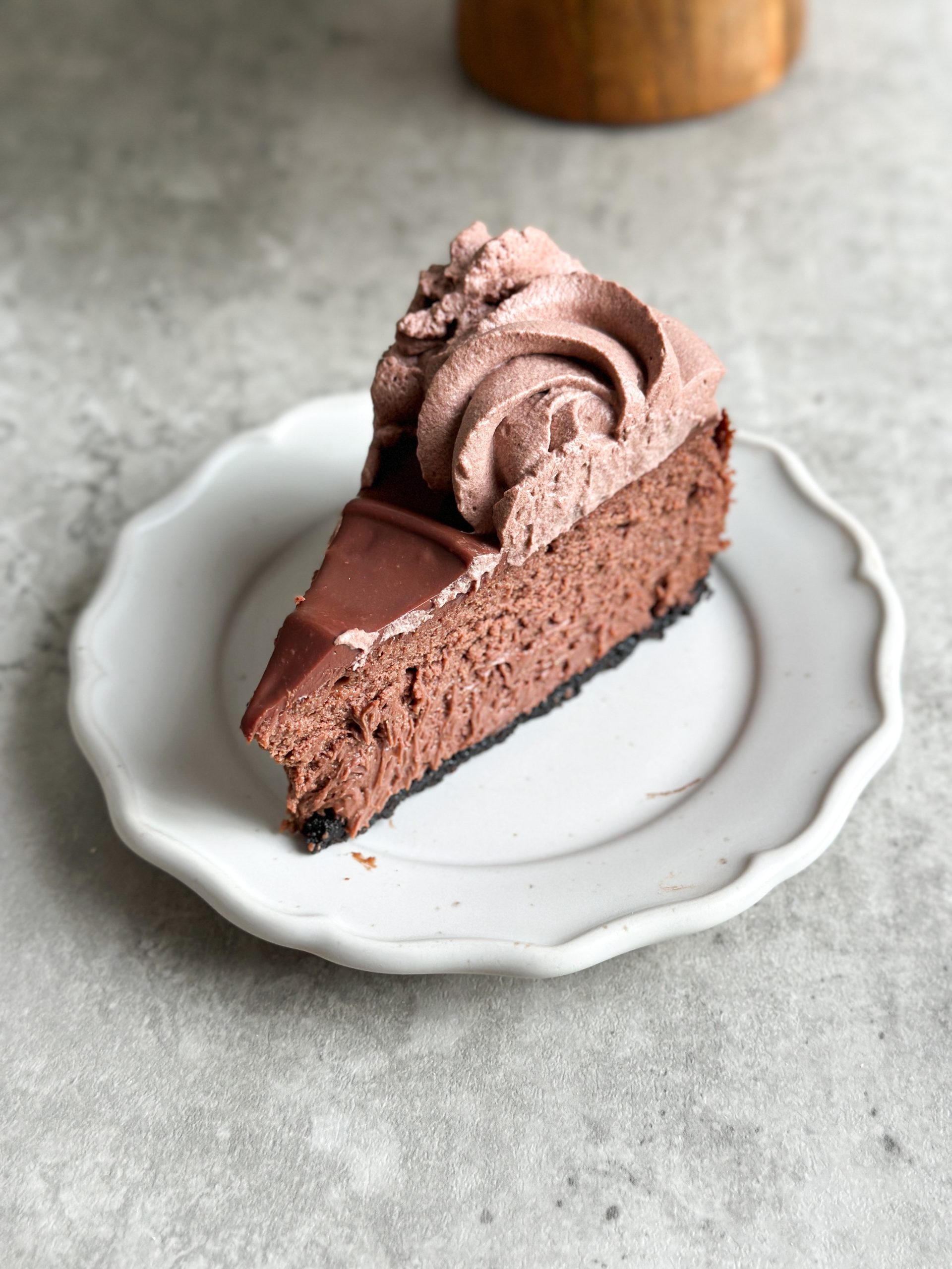 slice of chocolate cheesecake with creamy texture inside and ganache on top