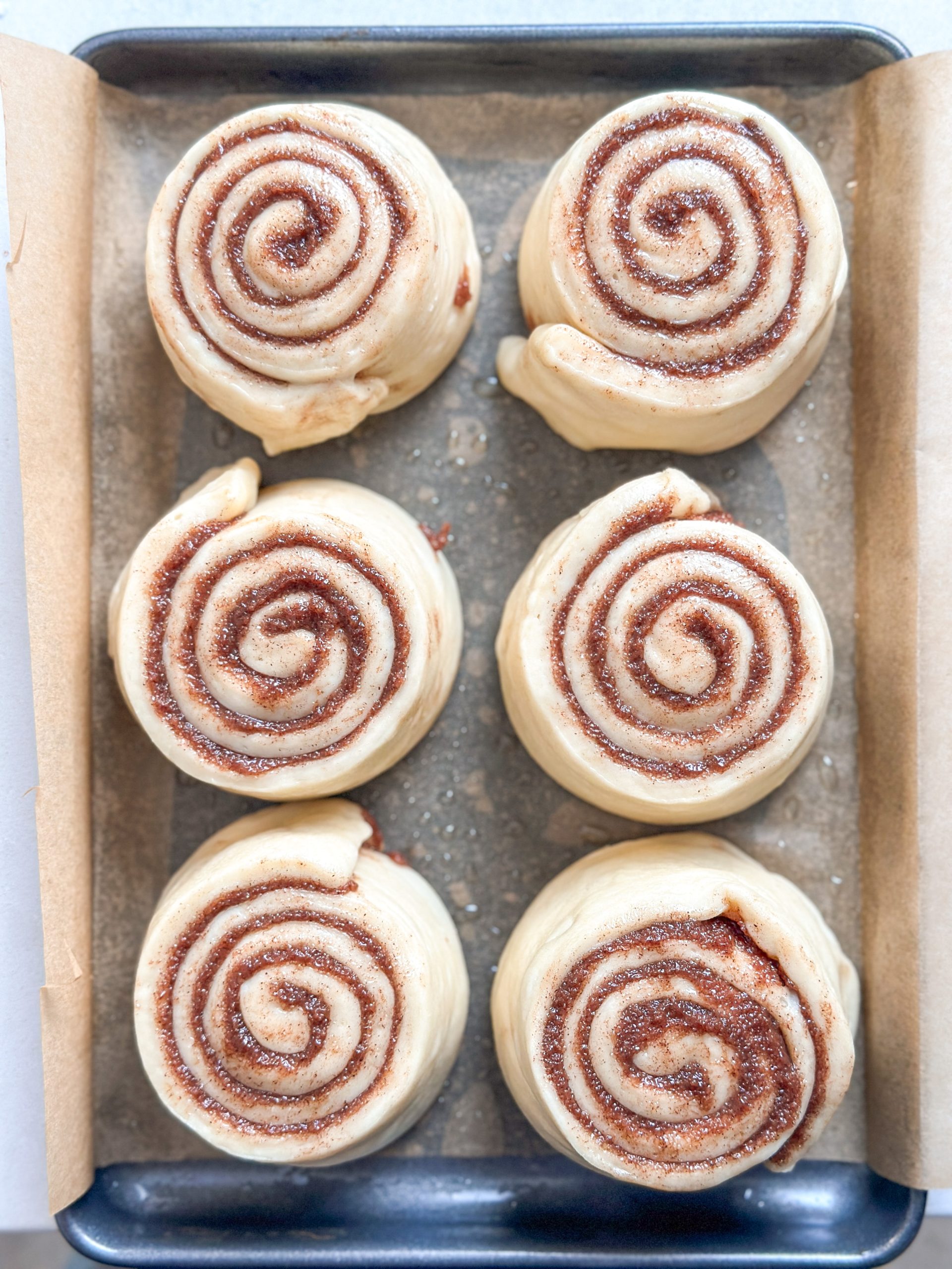 Small batch of 6 uncooked cinnamon rolls in an eighth pan