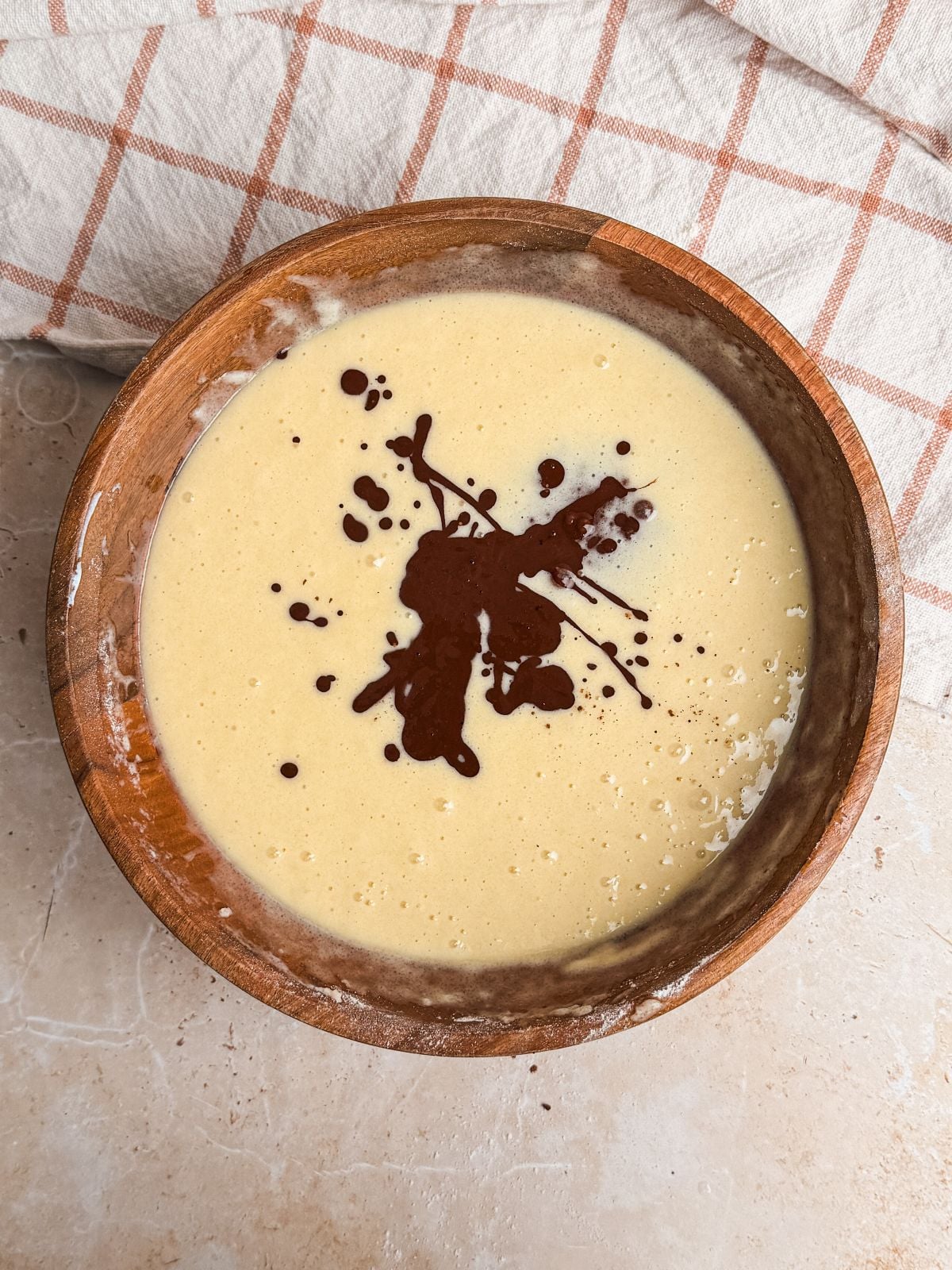 cocoa powder mixture poured into cake batter in a wooden bowl