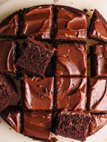 round chocolate cake covered with ganache frosting and cut into small slices, with some slices placed sideways