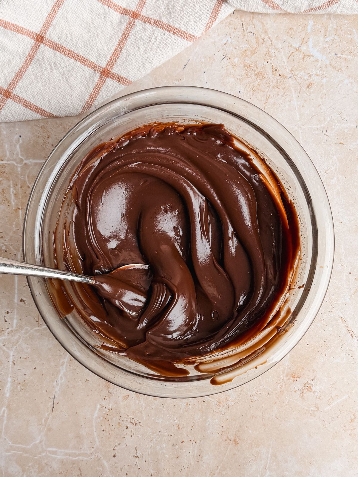 a glass bowl with a thick, spreadable chocolate ganache and a spoon