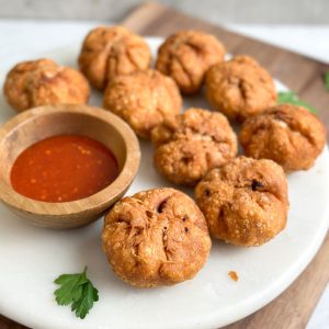 9 golden kachoris on a serving stand with sauce on the side