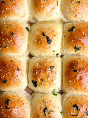 overhead image of 12 baked naan buns with a golden color and garlic butter brushed over them