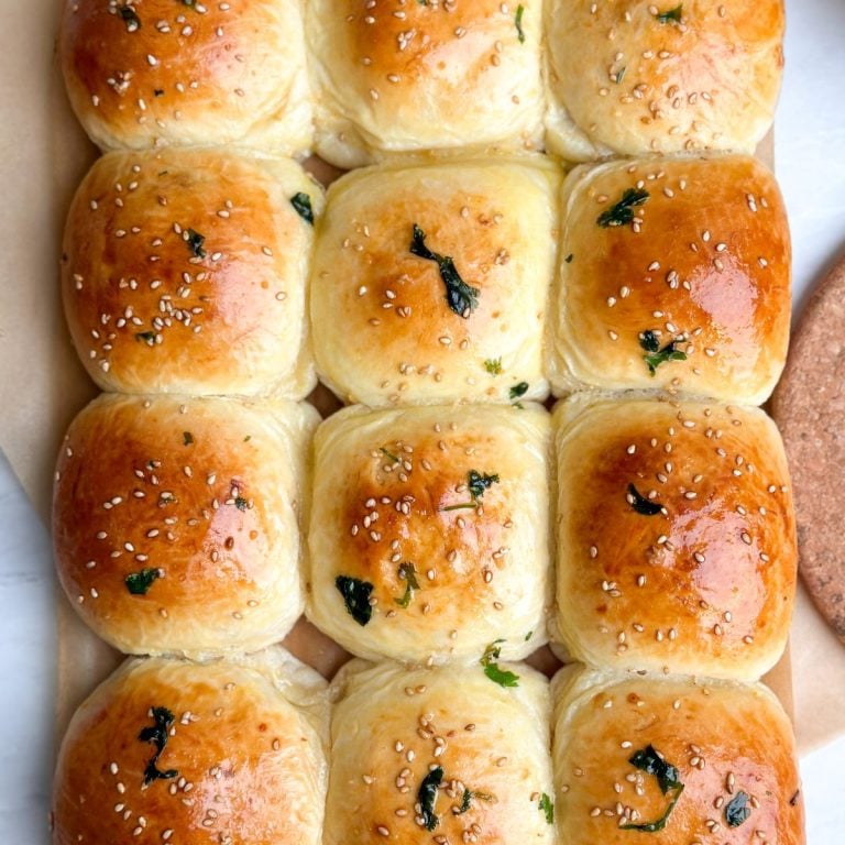 overhead image of 12 baked naan buns with a golden color and garlic butter brushed over them