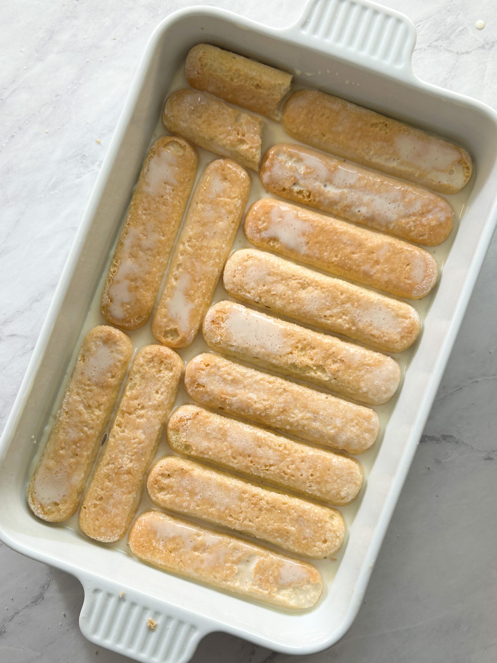 ladyfingers soaked in tres leches milk mixture in a dish