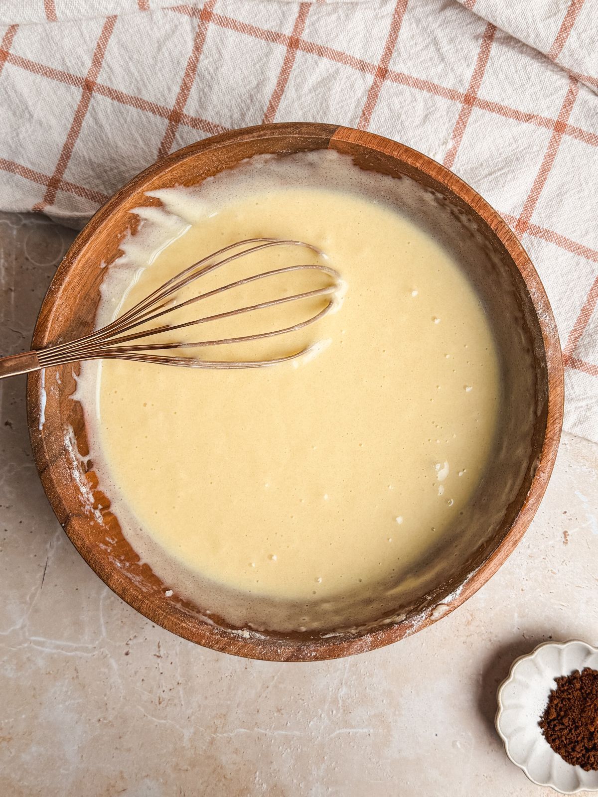 cake batter in a wooden bowl with a whisk in it