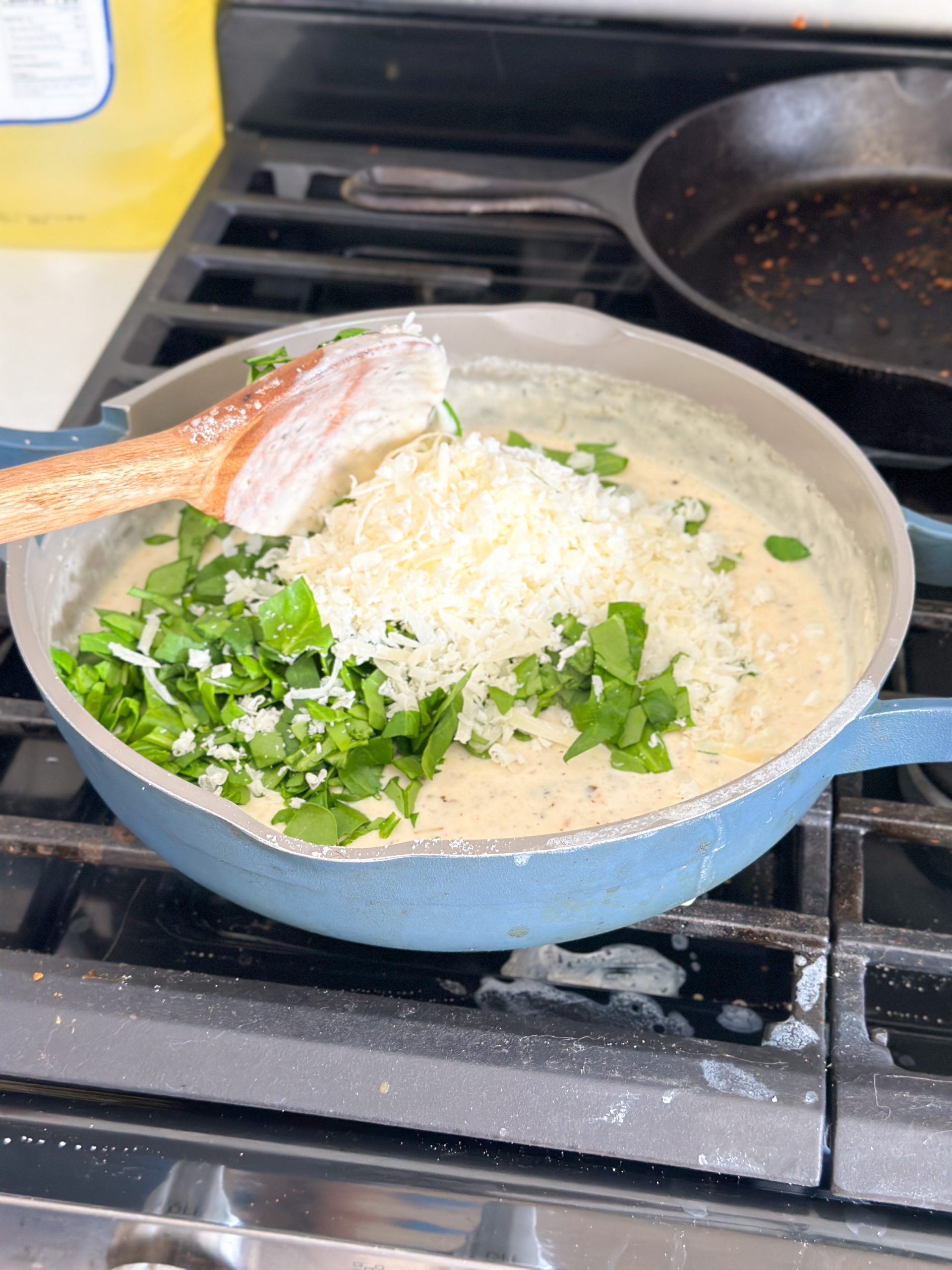 chopped spinach and grated parmesan cheese added to a pan with white sauce