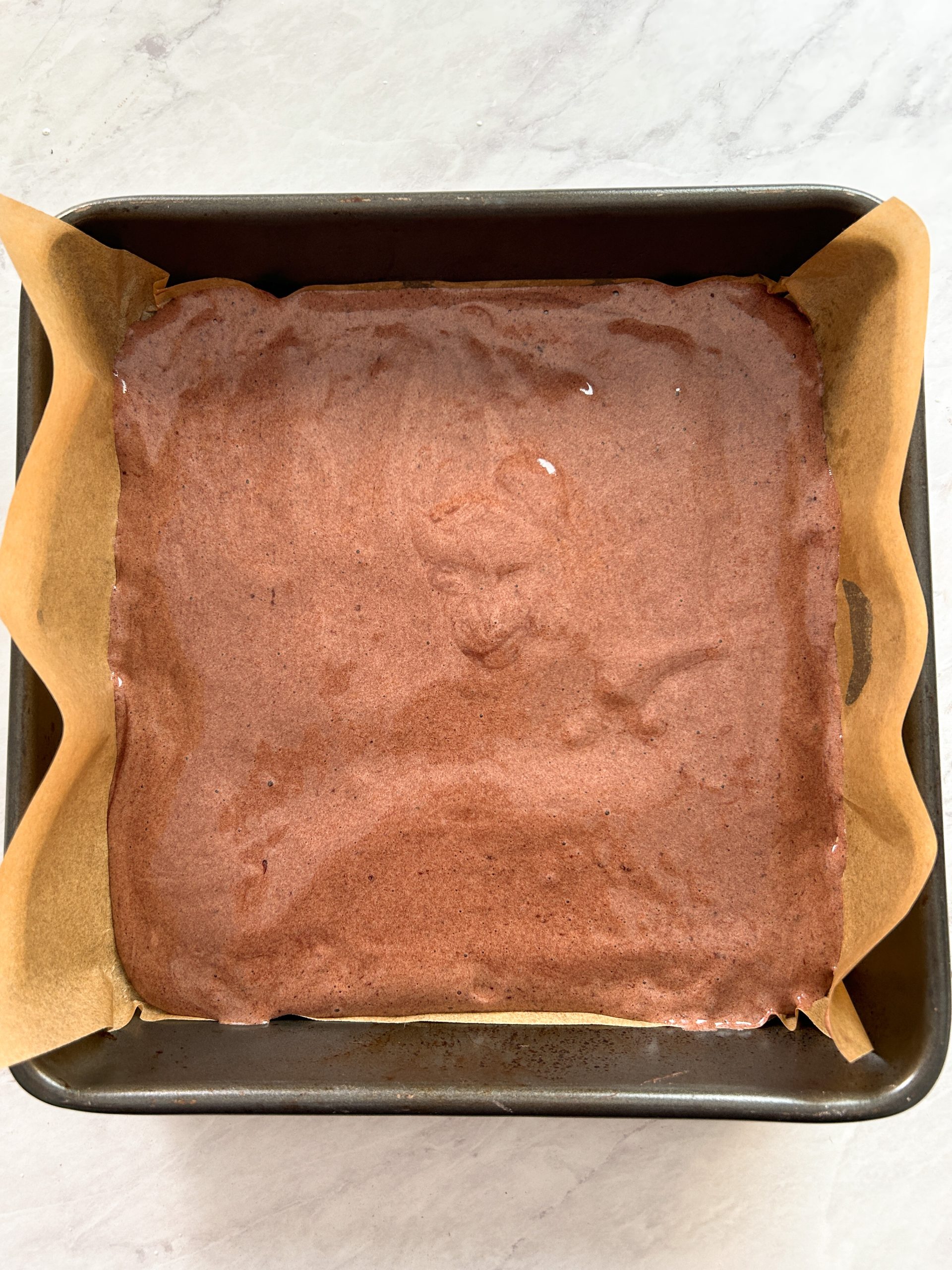 chocolate sponge cake batter in a square pan