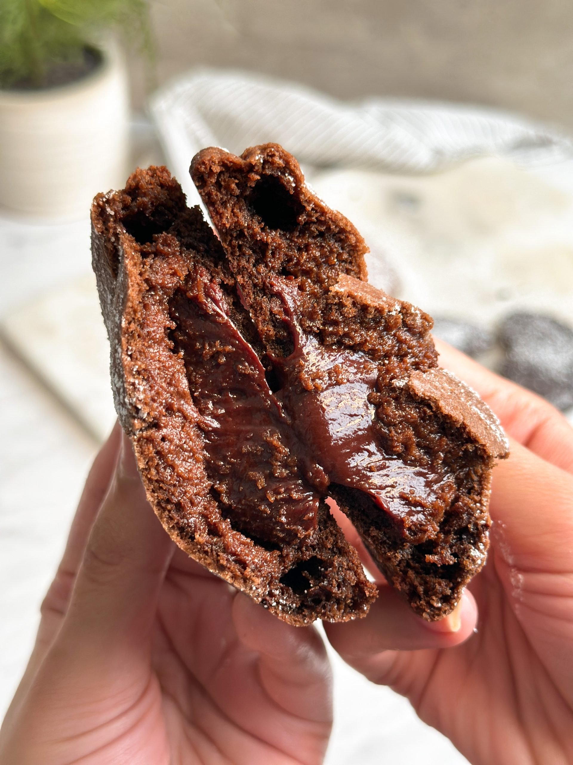 chocolate lava cookie broken in half in 2 hands revealing molten chocolatey interior