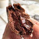chocolate lava cookie broken in half in 2 hands revealing molten chocolatey interior