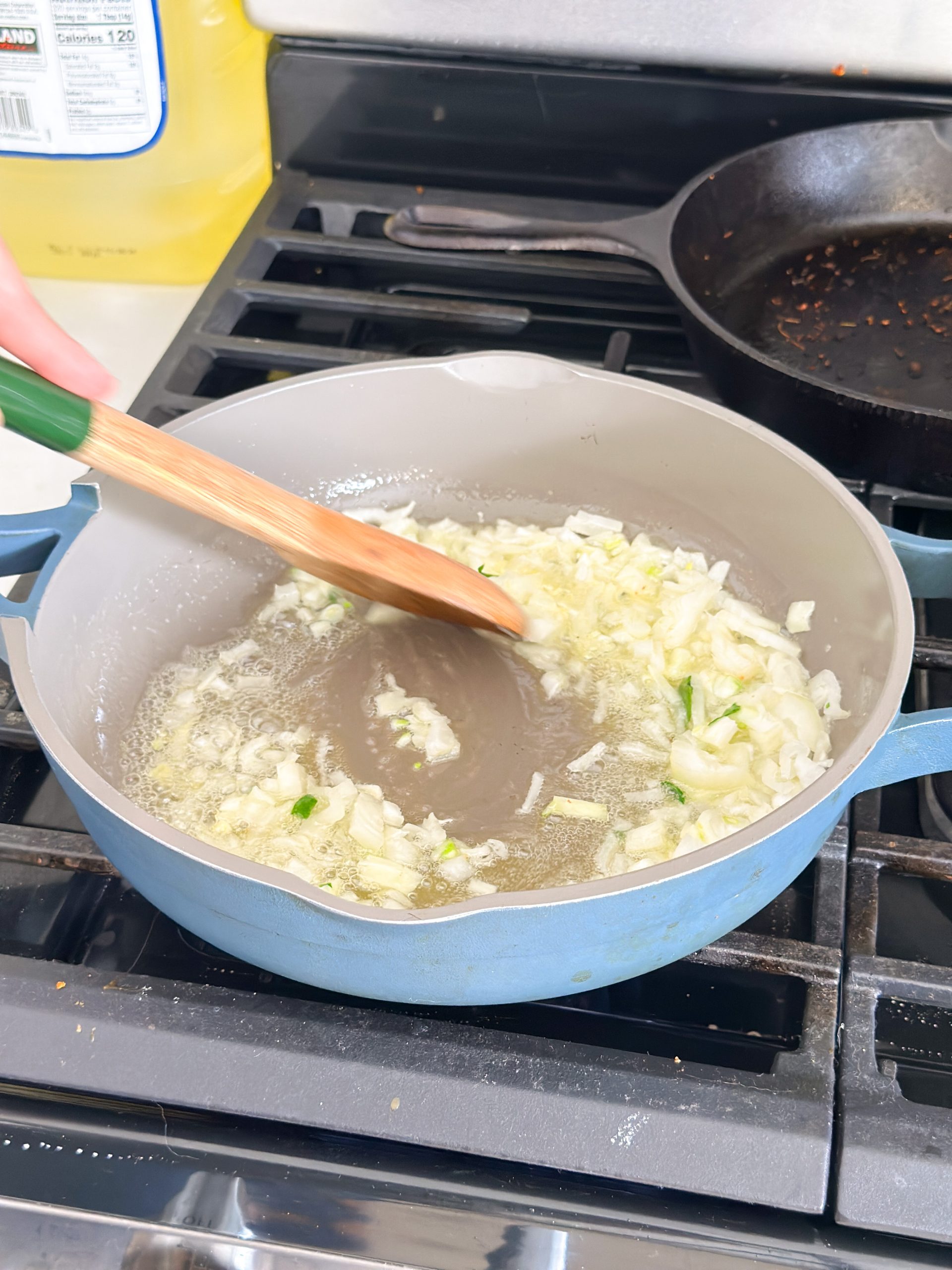 onion being sauted in butter in a blue nonstick pan
