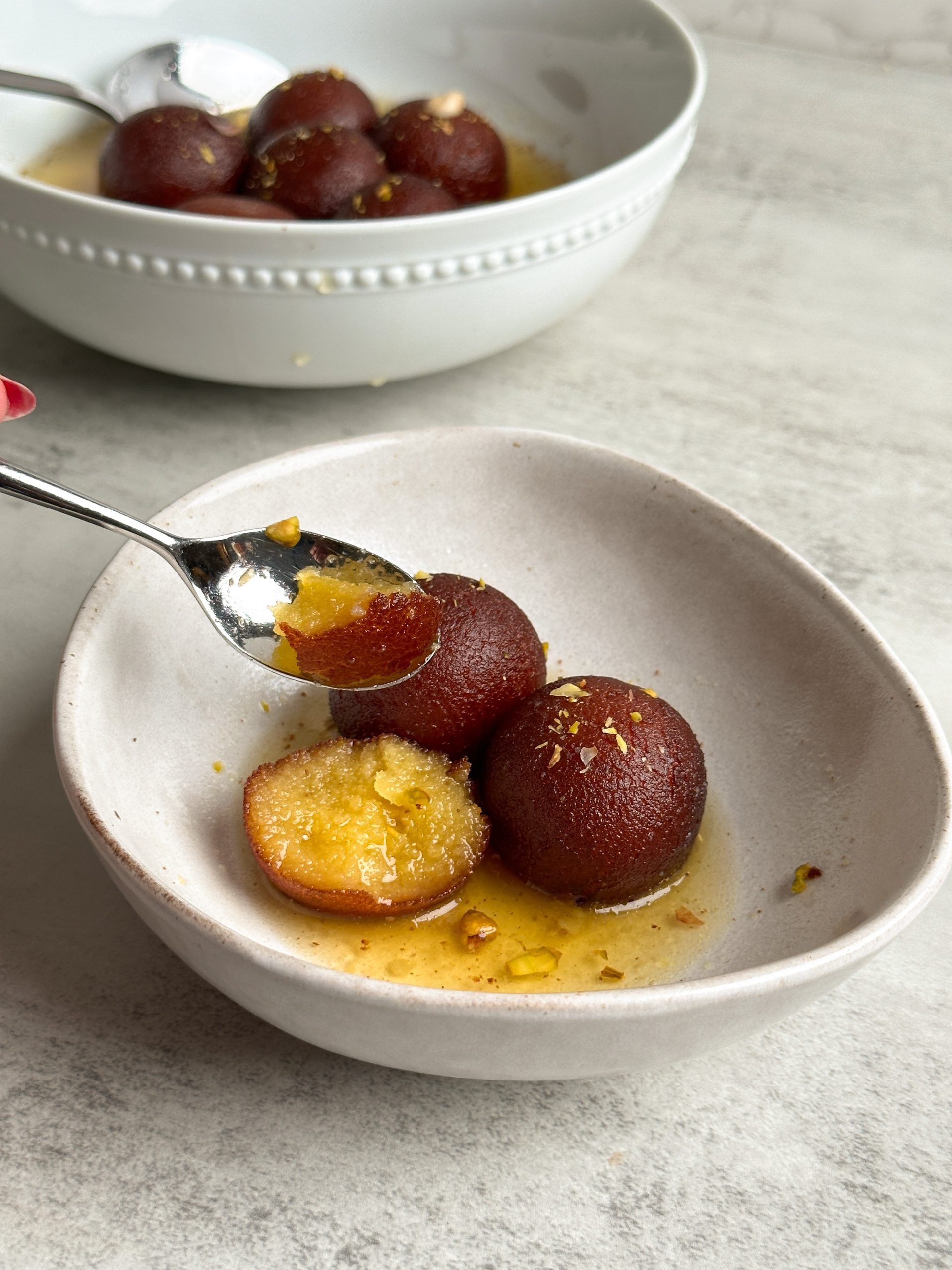 spoon taking bite from gulab jamun revealing moist interior