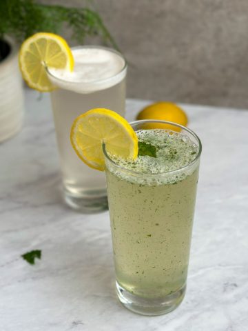 2 glasses with mint lemonade decorated with lemon slices