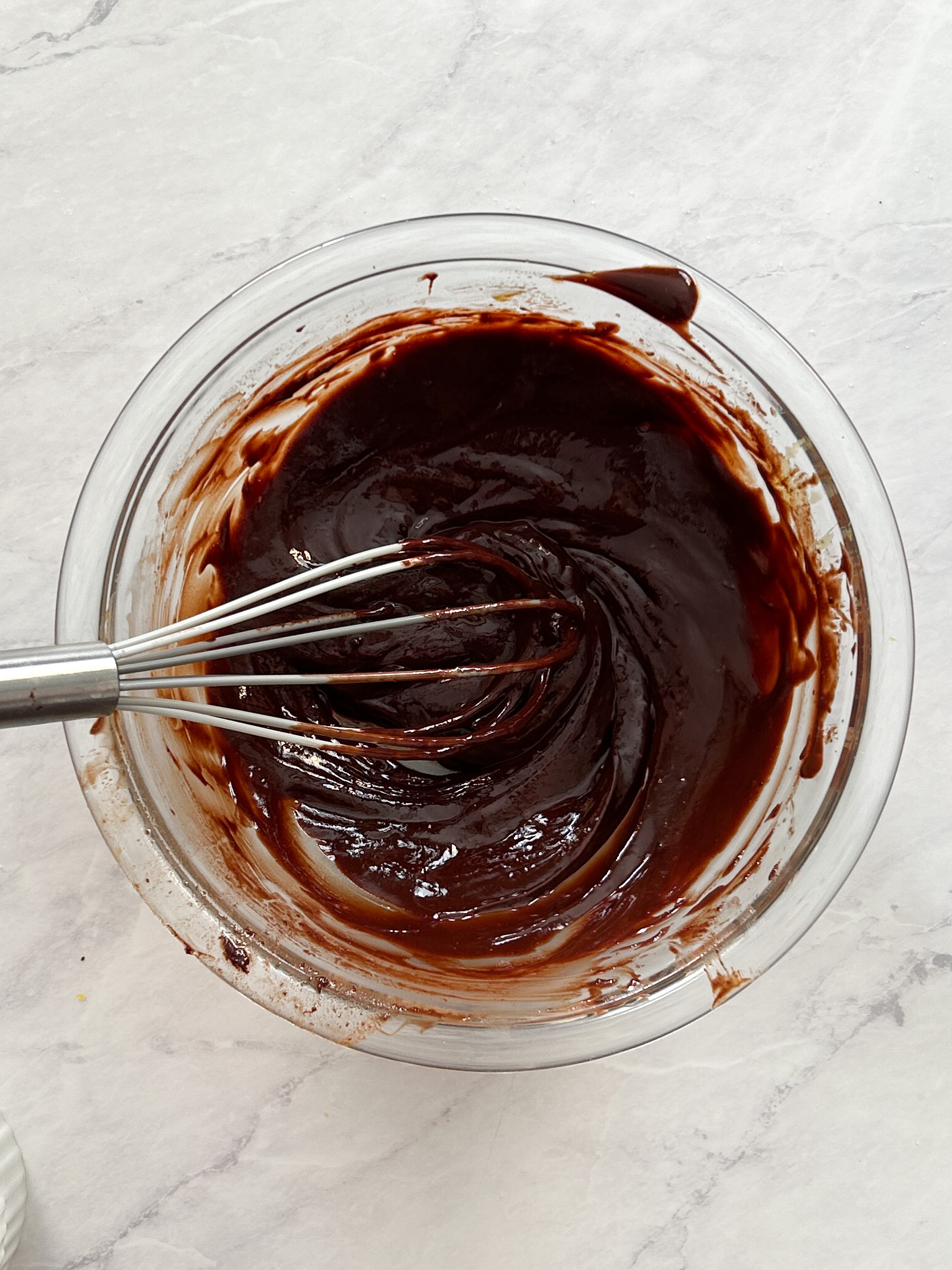 shiny chocolate batter in a  bowl with a whisk