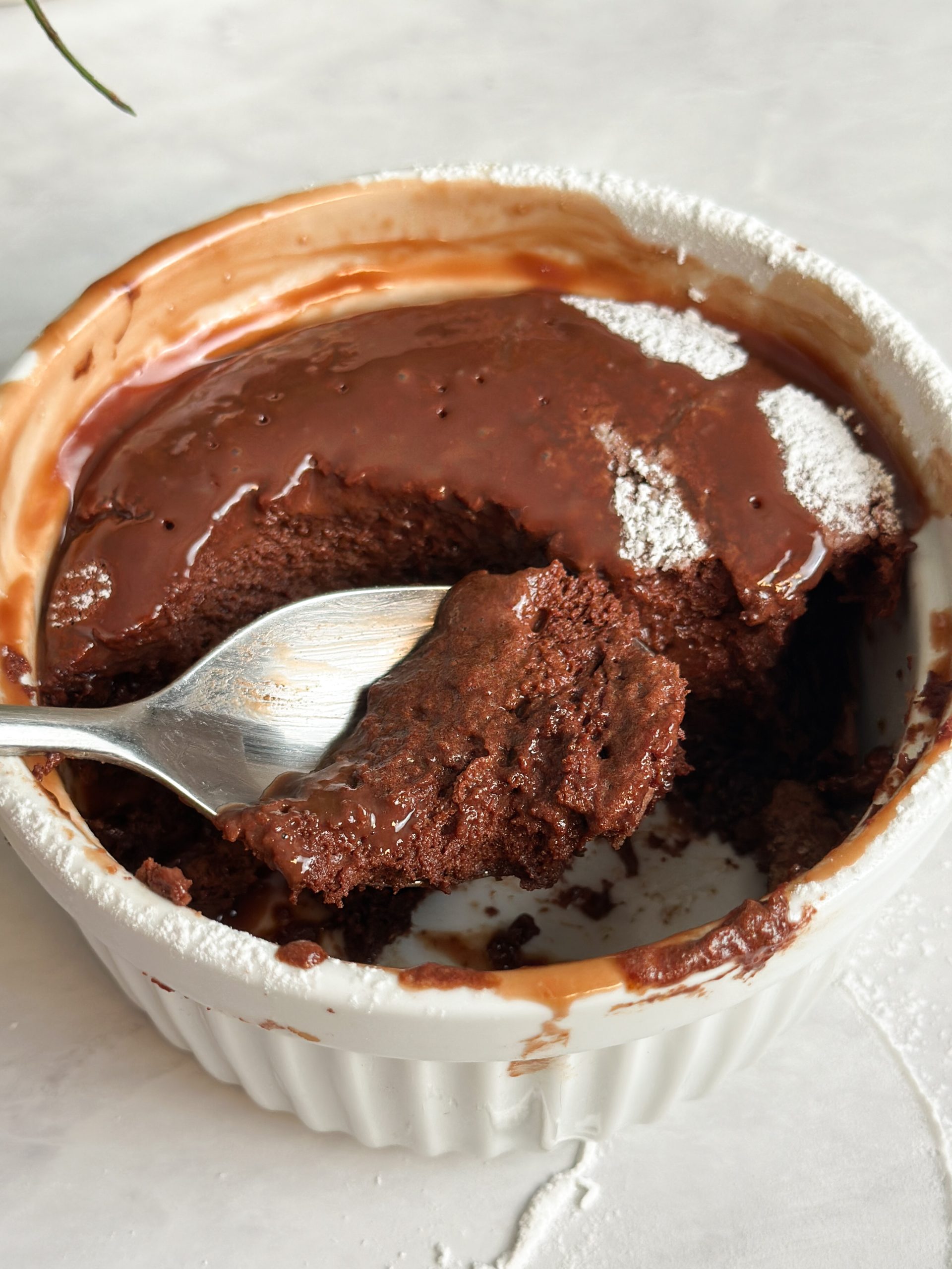 Spoon taking bite out of chocolate souffle showing light and airy texture inside