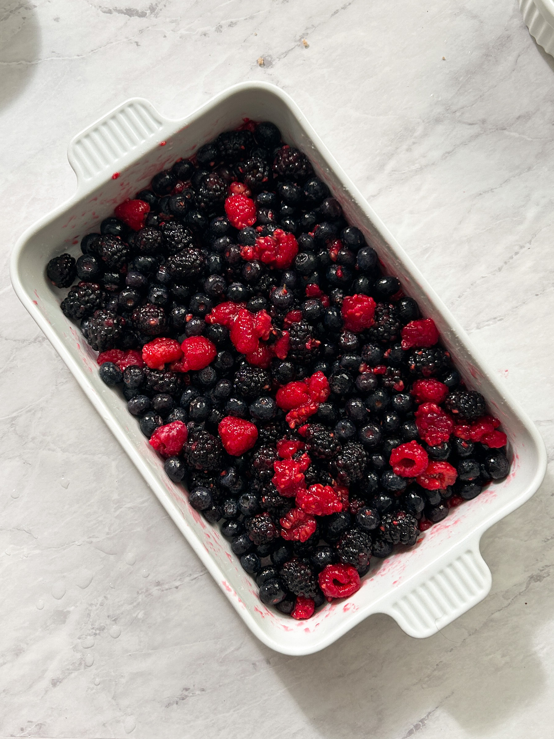 freshly washed raspberries blueberries and blackberries in a casserole dish