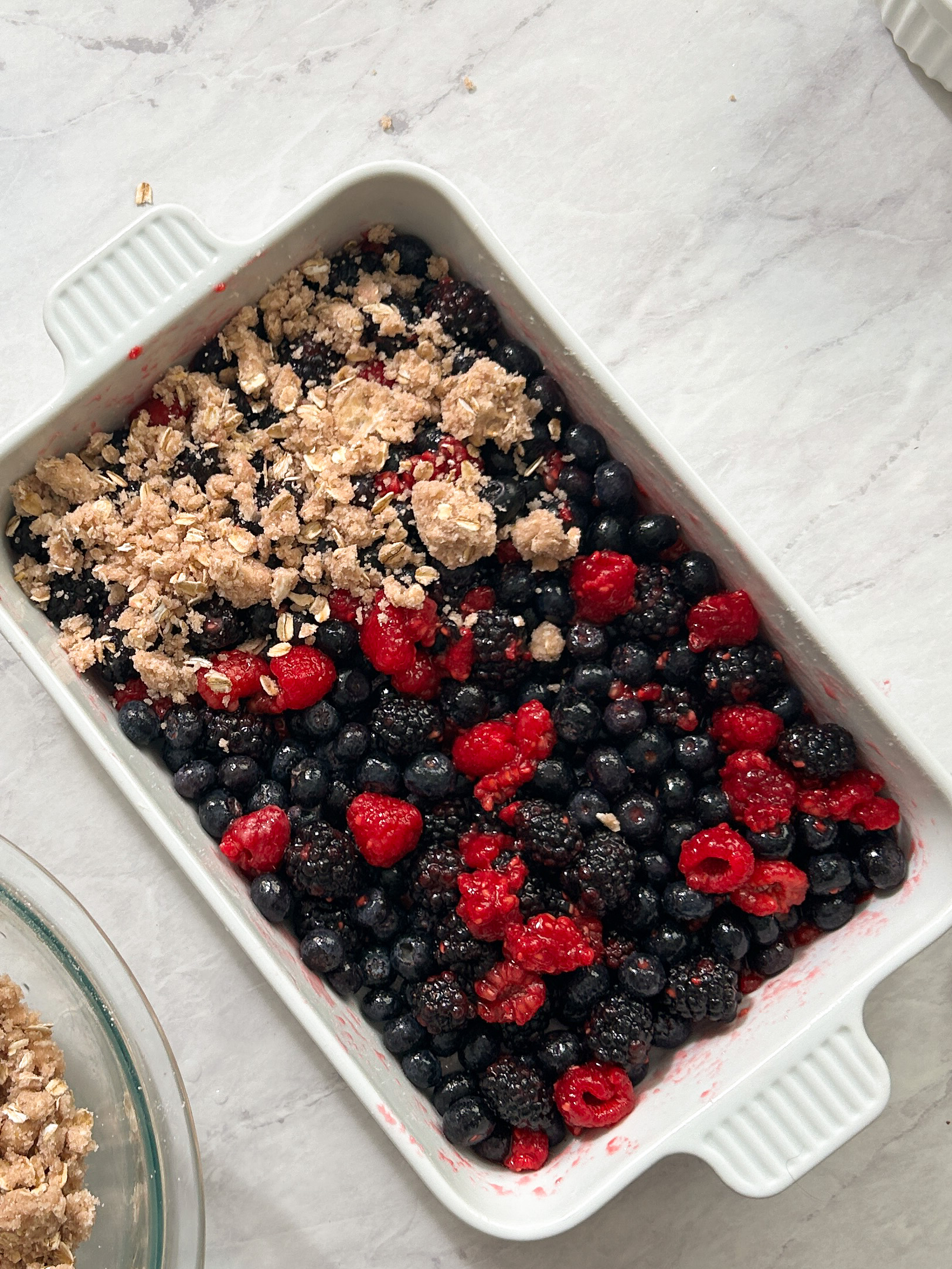 topping berry filling with oat crumble in a pan