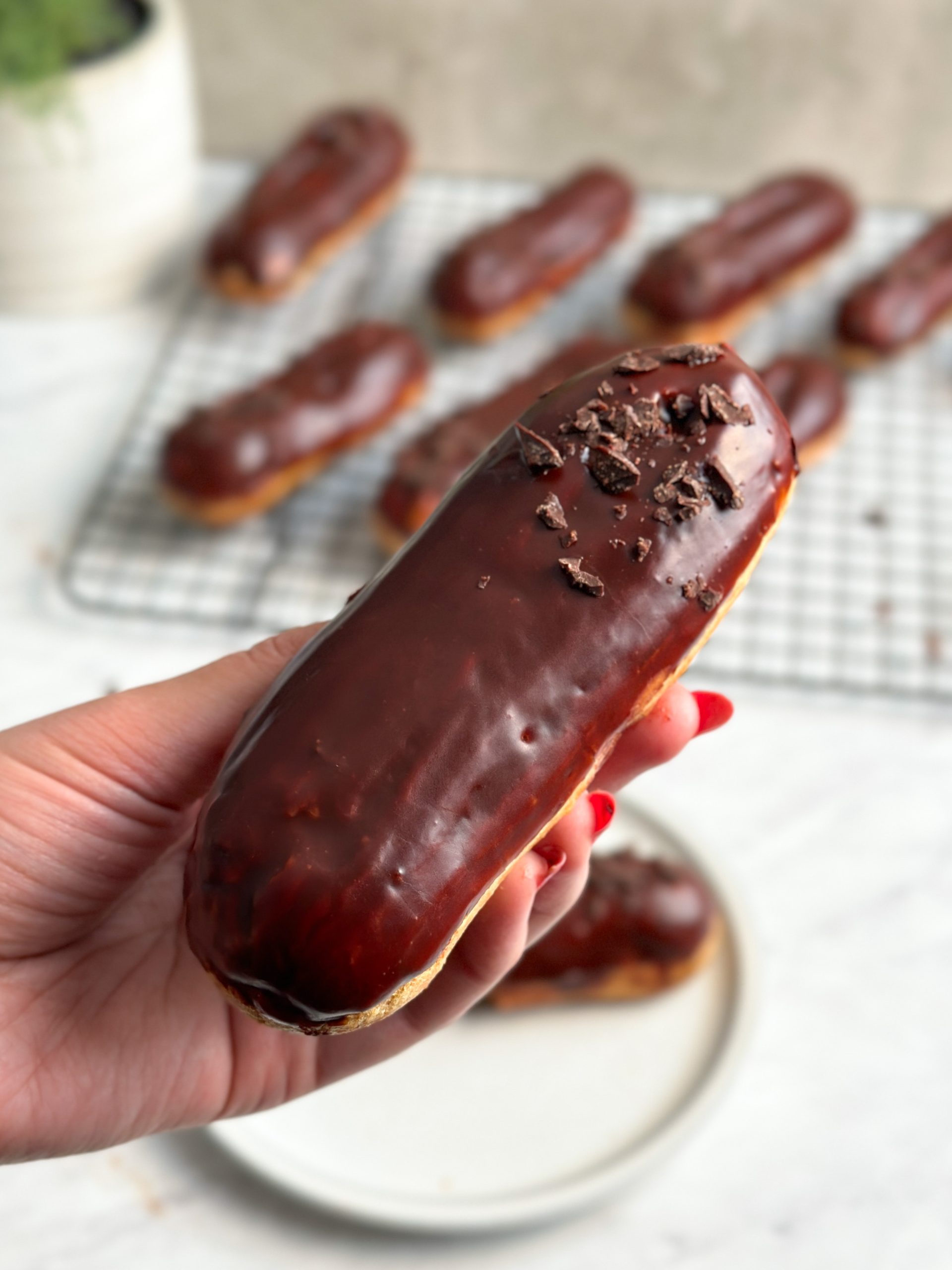 chocolate eclair in a hand with more in the background