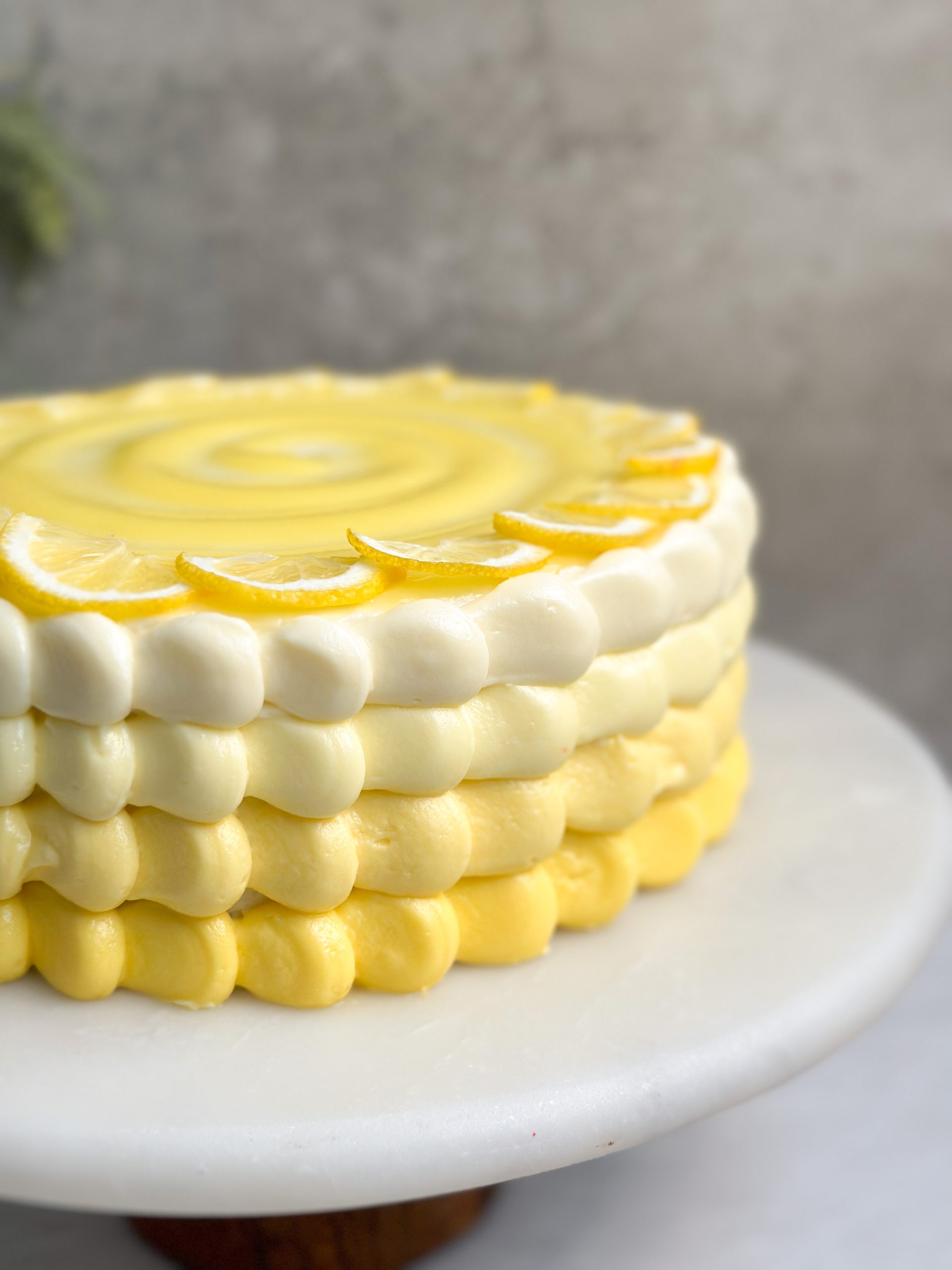 close up of lemon cake showing pretty ombre dollops on the side in varying shades of yellow