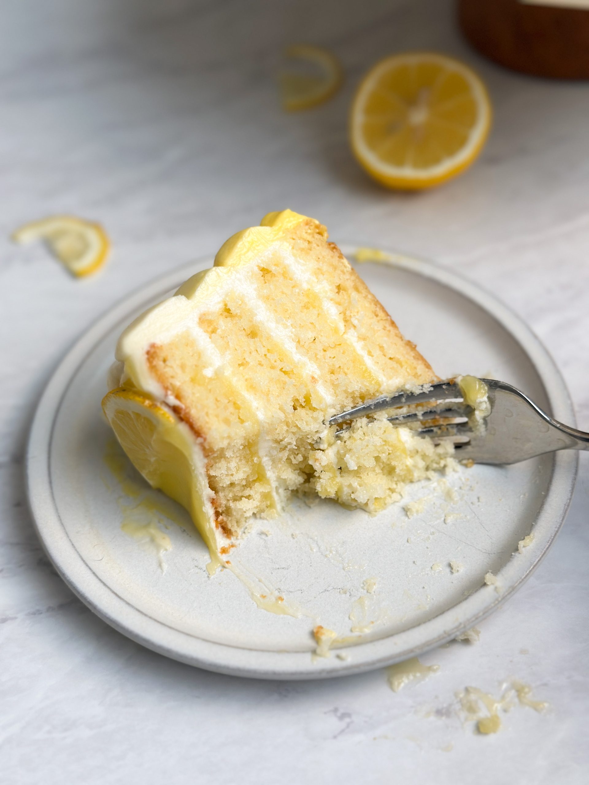 slice of lemon cake on a small plate with a fork taking out a bite