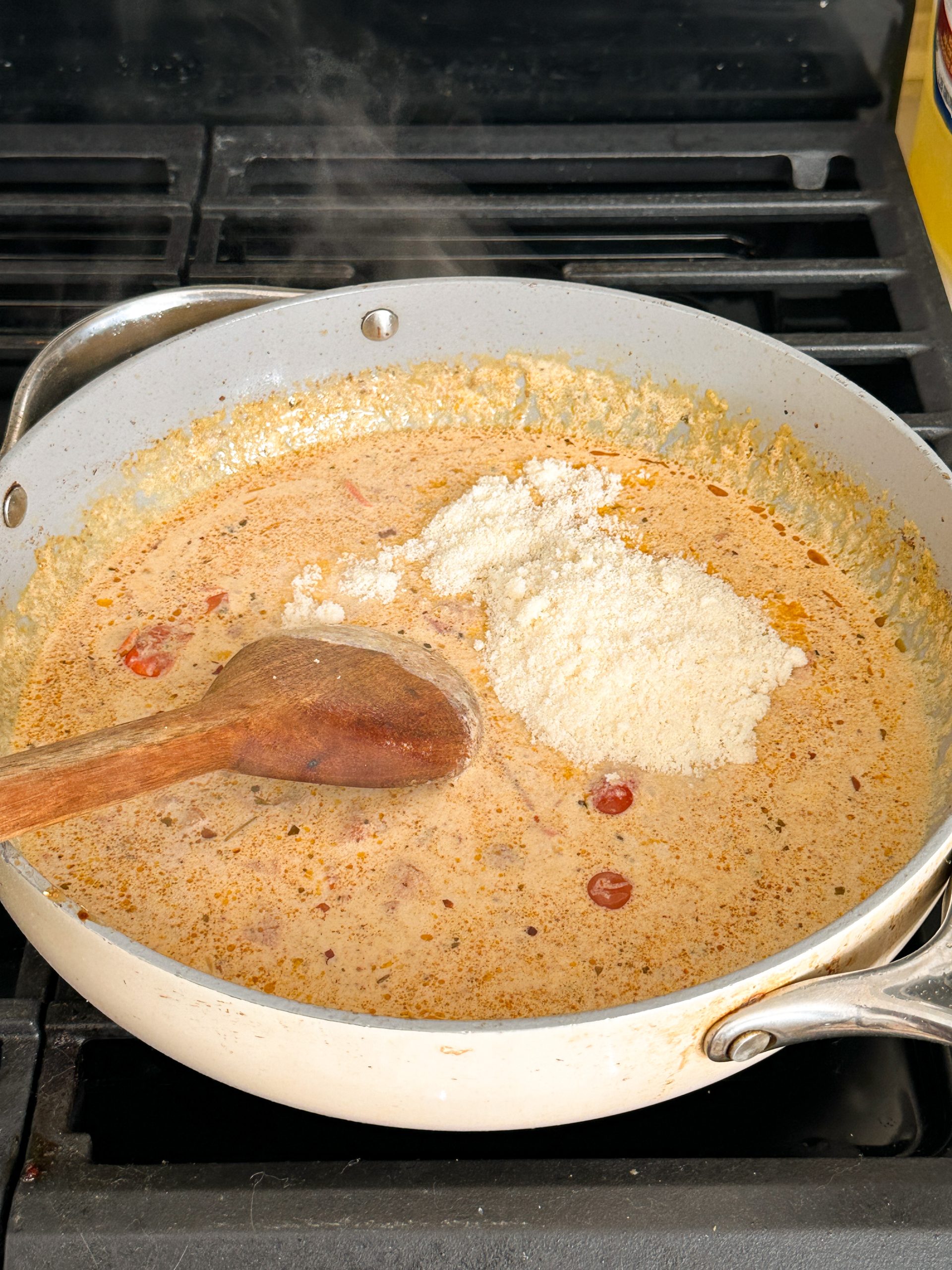 grated parmesan cheese being mixed into tuscan pasta sauce 