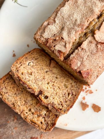 overhead image of a loaf of banana bread with cinnamon crunch with 2 slices cut revealing moist interior