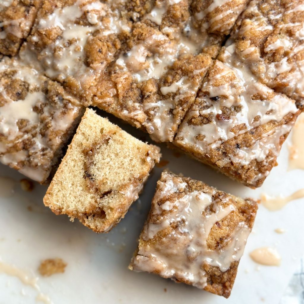 slices of Coffee cake with coffee streusel topping and coffee icing on a marble serving board, with one slice turned sideways to reveal moist and soft interior and more streusel inside