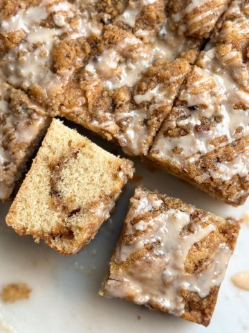 slices of Coffee cake with coffee streusel topping and coffee icing on a marble serving board, with one slice turned sideways to reveal moist and soft interior and more streusel inside