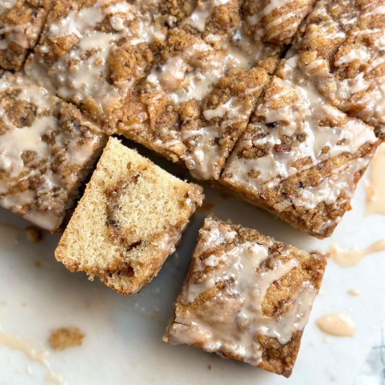slices of Coffee cake with coffee streusel topping and coffee icing on a marble serving board, with one slice turned sideways to reveal moist and soft interior and more streusel inside