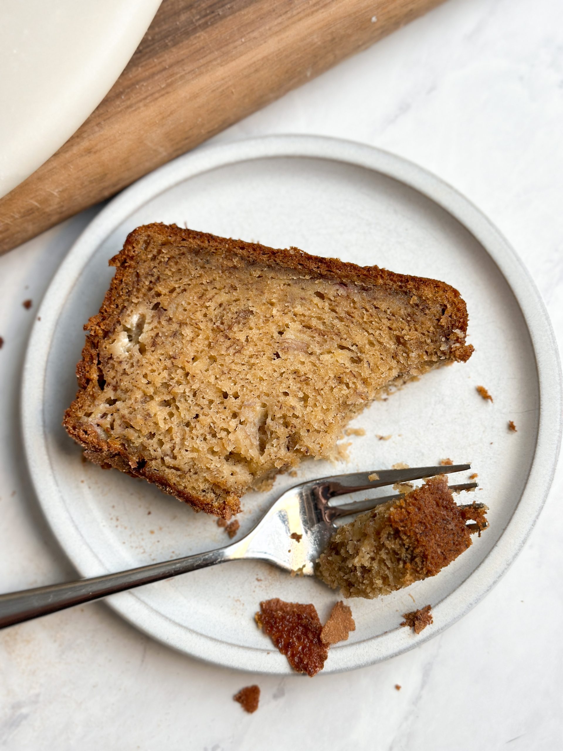 fork taking a bite out of a moist slice of banana bread in a small plate