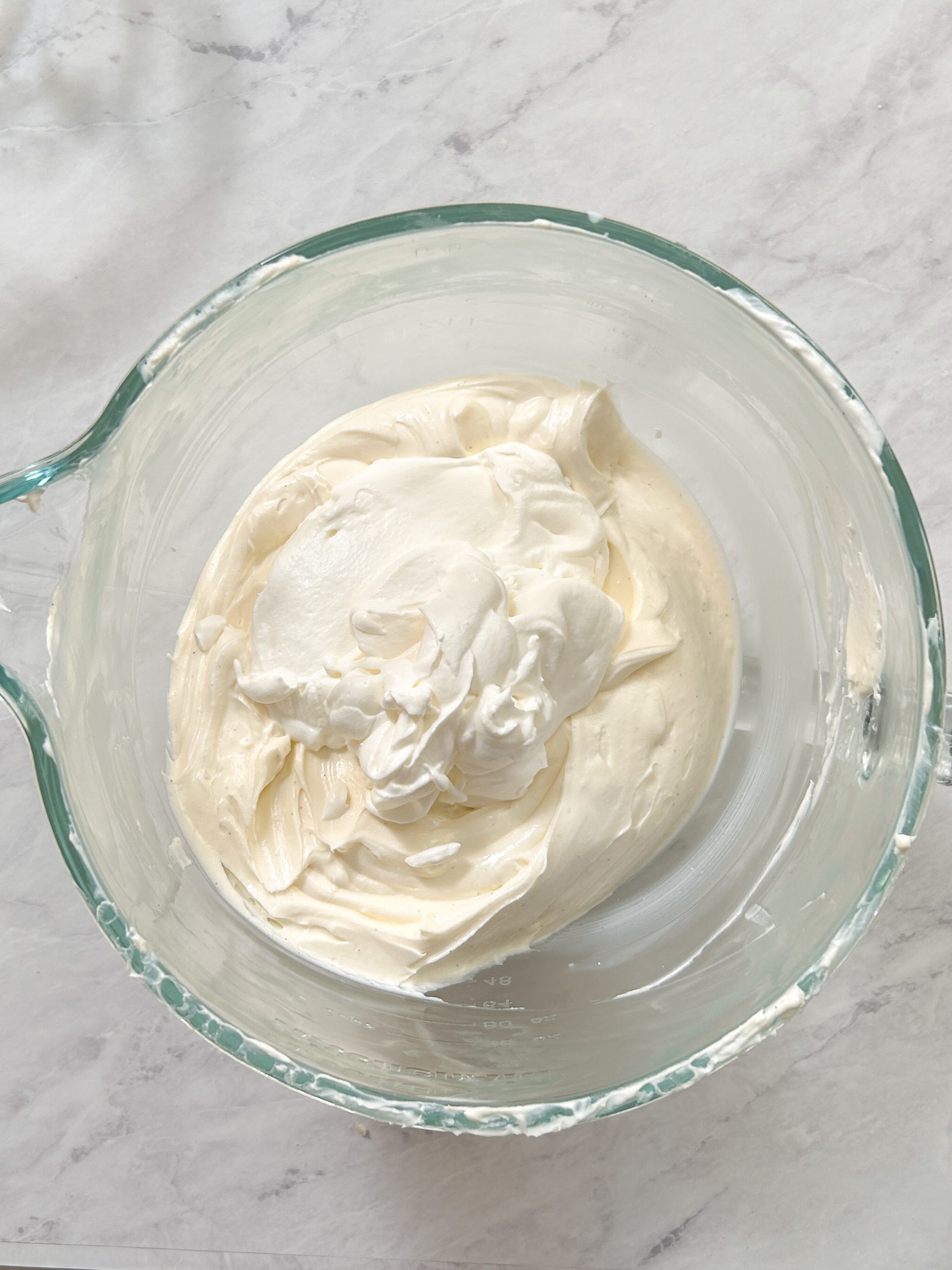 sour cream and lemon juice added to cream cheese and sugar mixture in a glass bowl