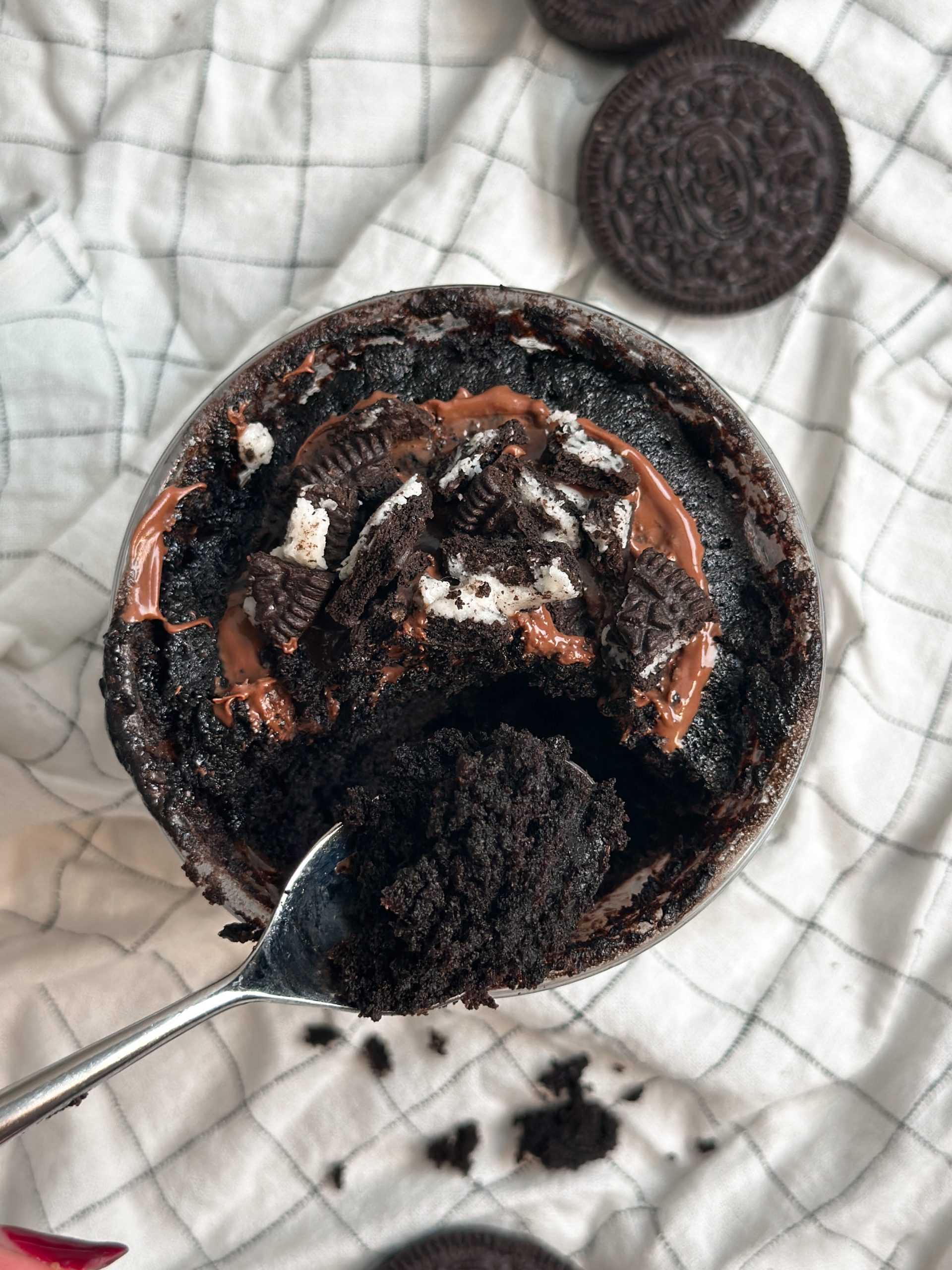 spoon taking bite out of oreo chocolate mug cake revealing moist chocolatey interior, pic from the top