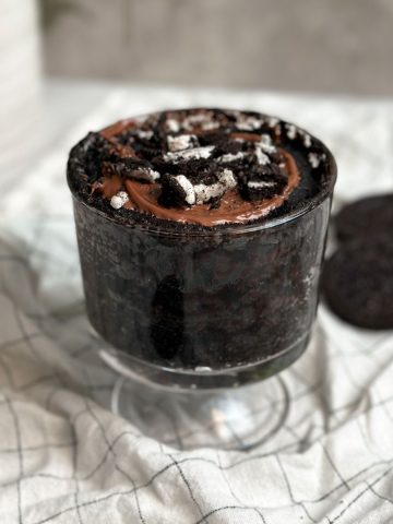 oreo chocolate mug cake in a glass mug topped with melted chocolate and crushed oreos