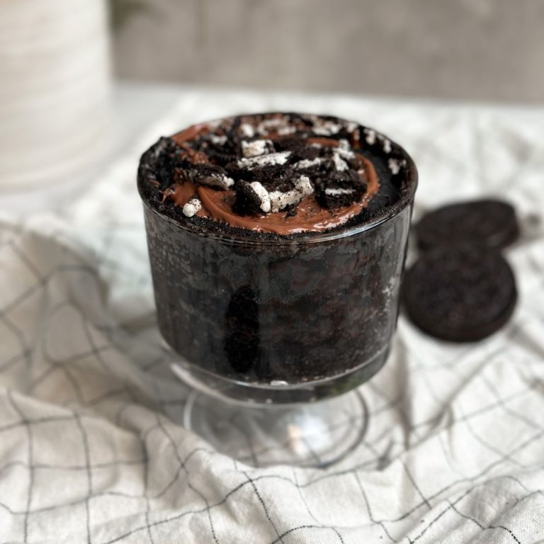 oreo chocolate mug cake in a glass mug topped with melted chocolate and crushed oreos