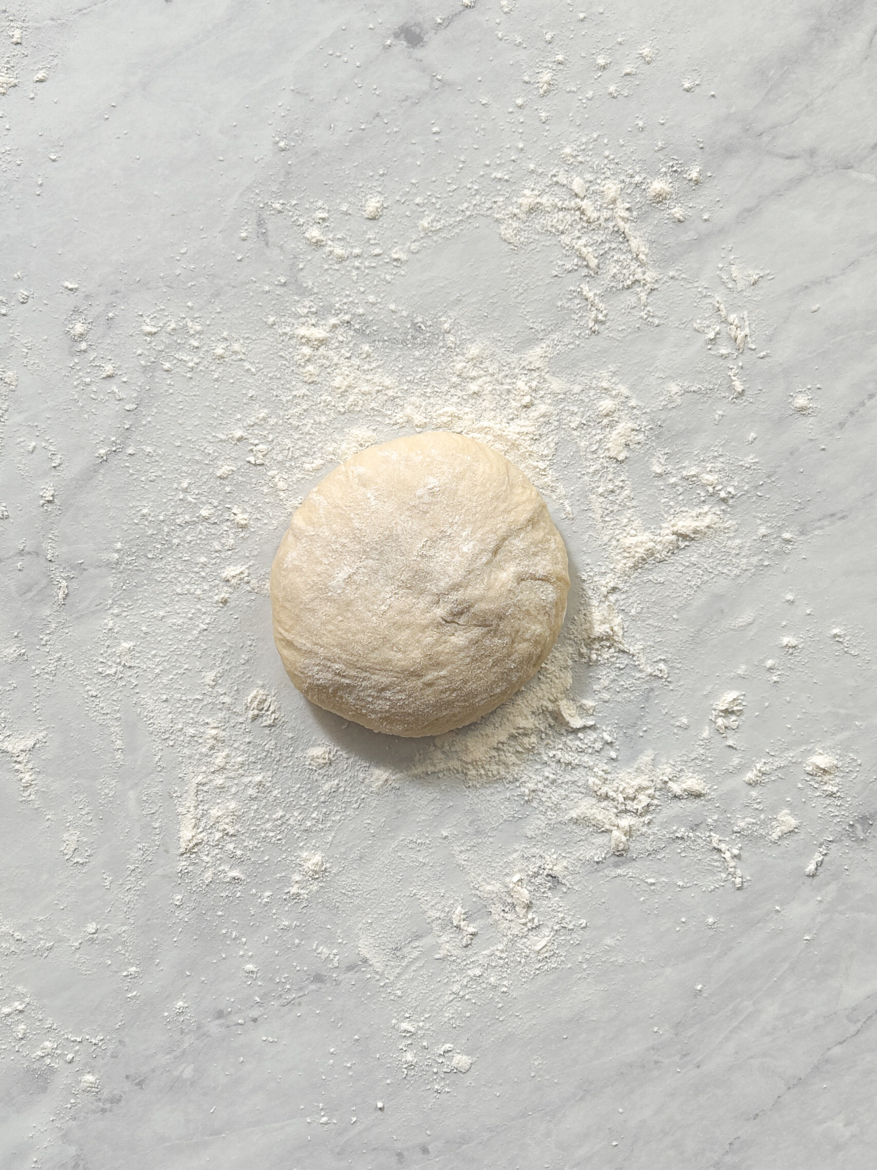 pizza dough rolled into a ball on a lightly floured surface