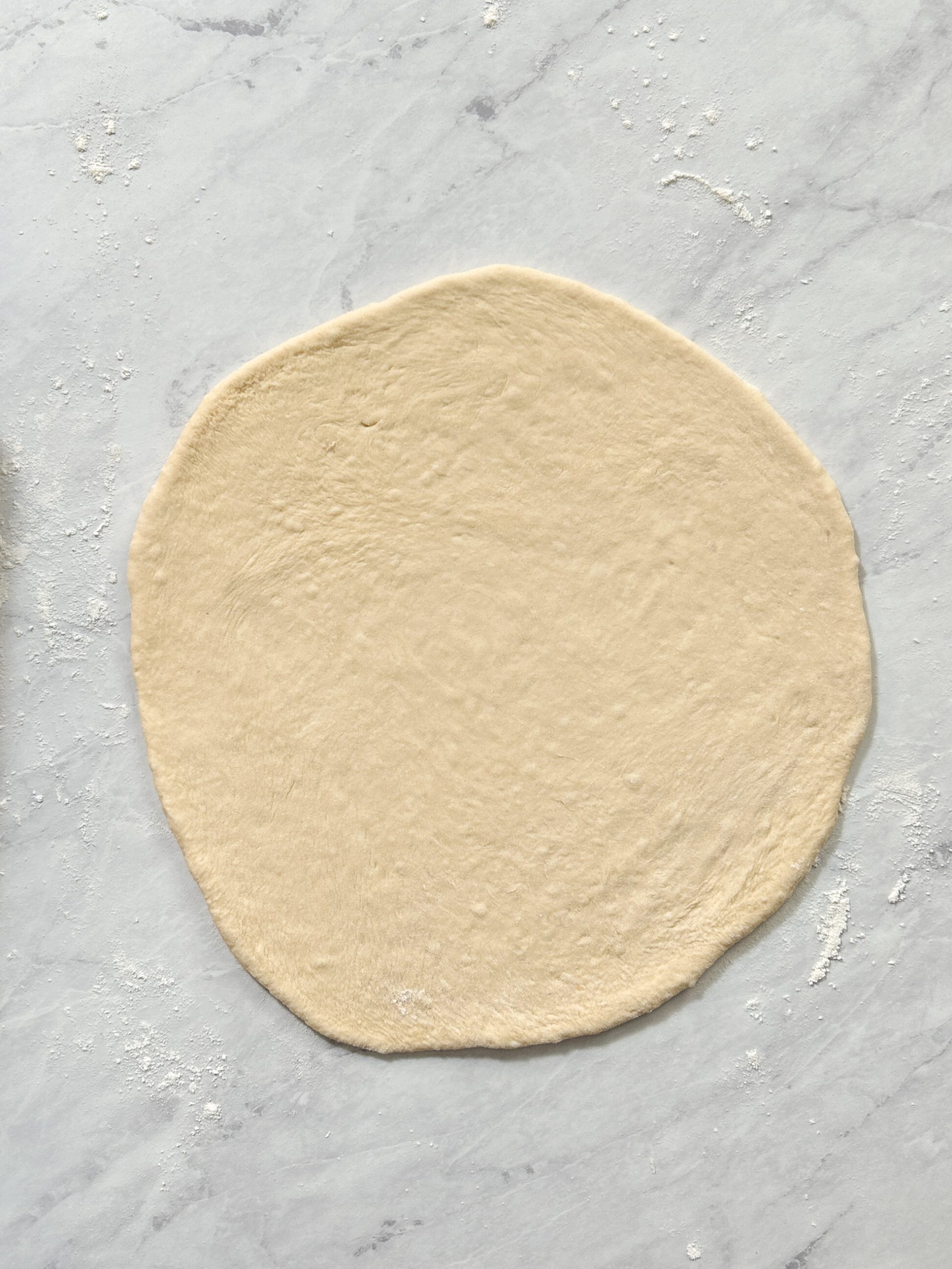 pizza dough rolled into a thin circle shape