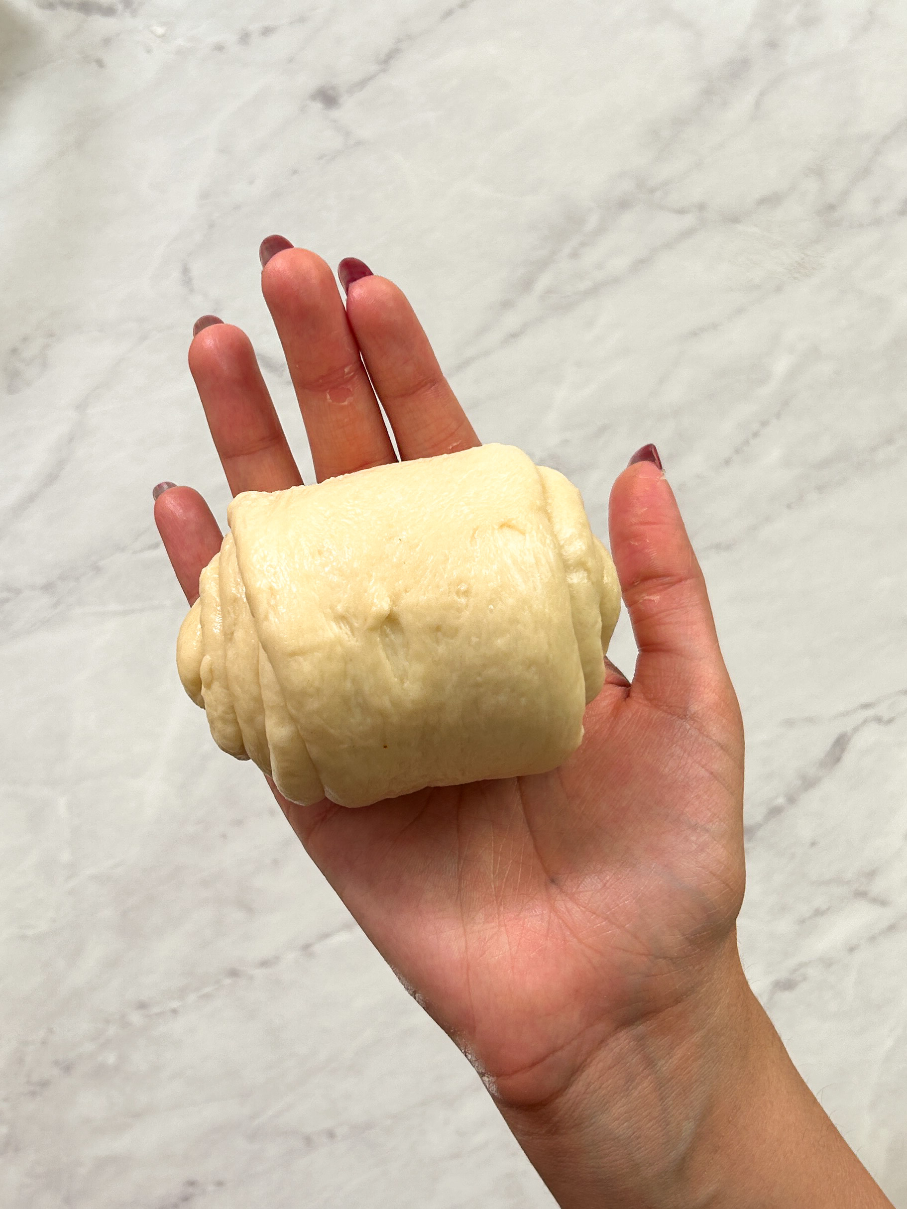 a cylindrical roll of dough in a hand