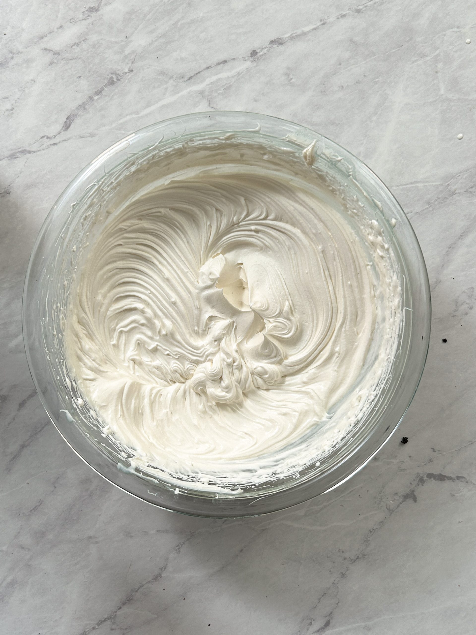 whipped cream with cream cheese whisked to stiff peaks in a glass bowl