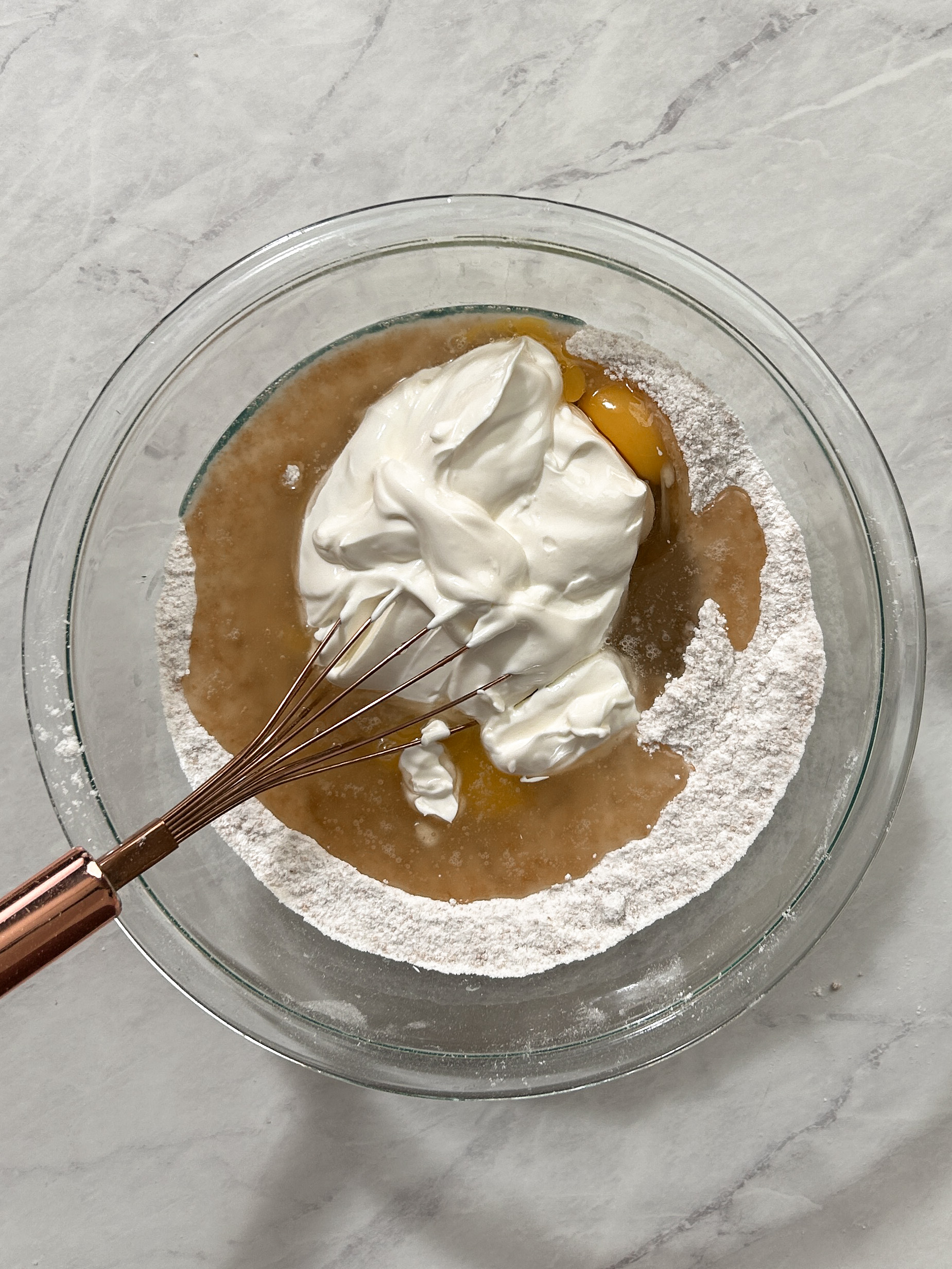 sour cream, oil and eggs added to dry ingredients in a bowl with a whisk
