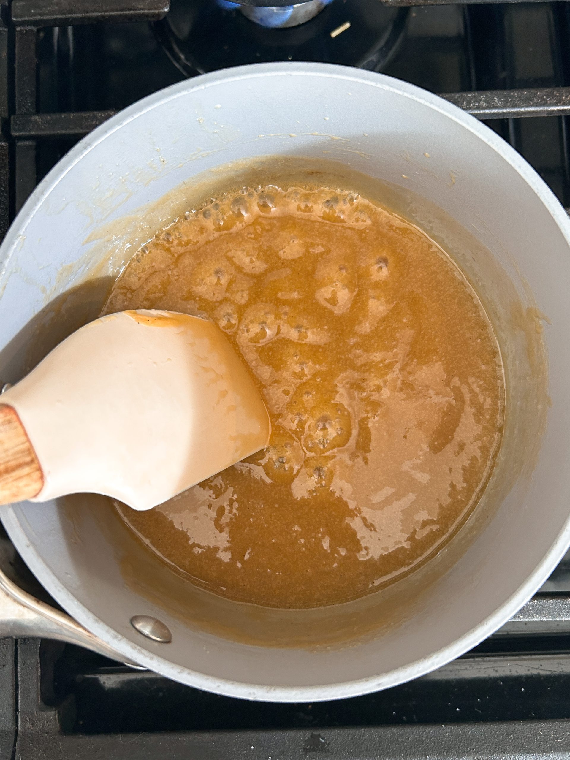 saucepan with sticky toffee sauce and spatula stirring