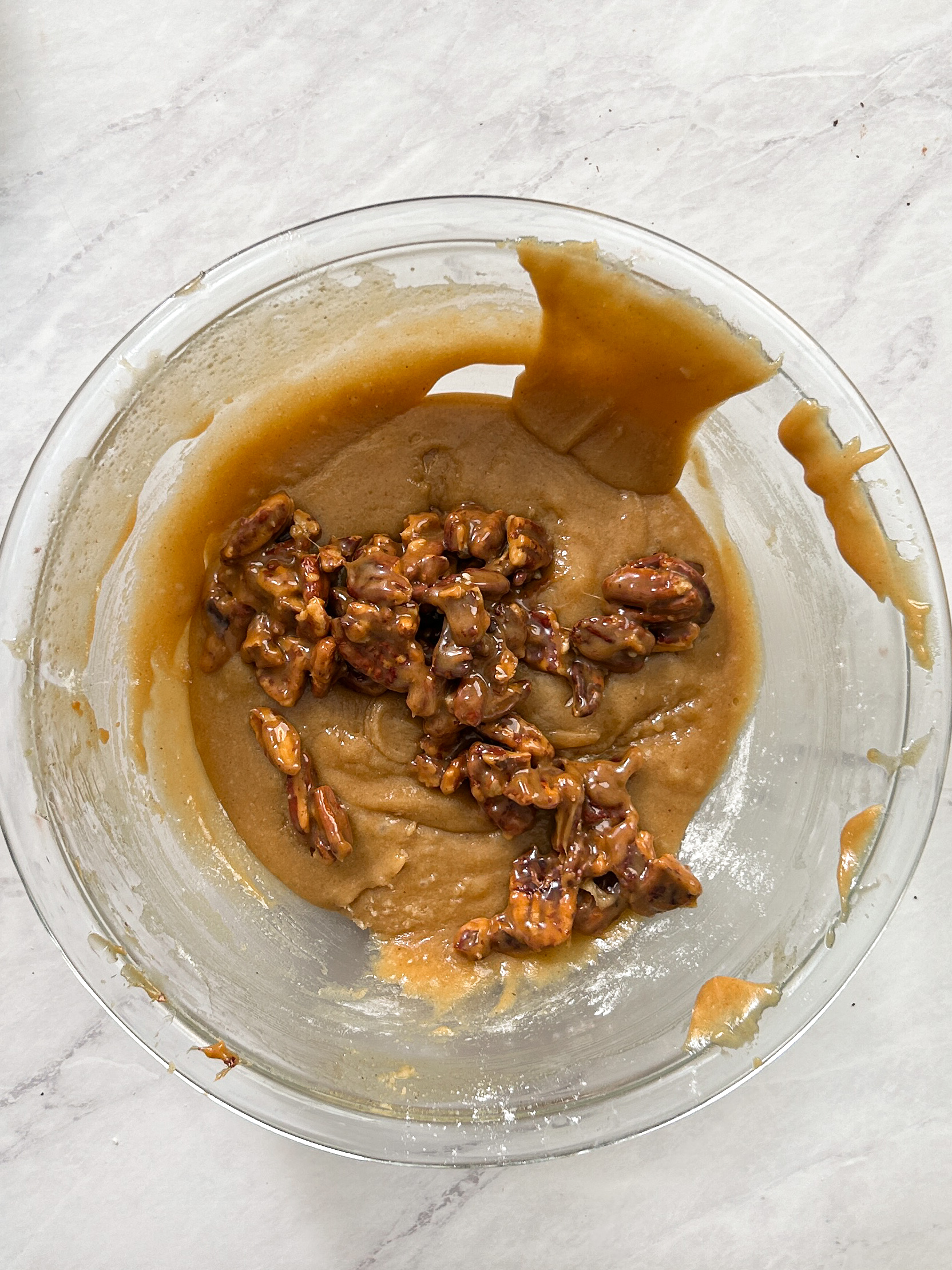 cookie dough in a glass bowl with salted caramel pecans added to it