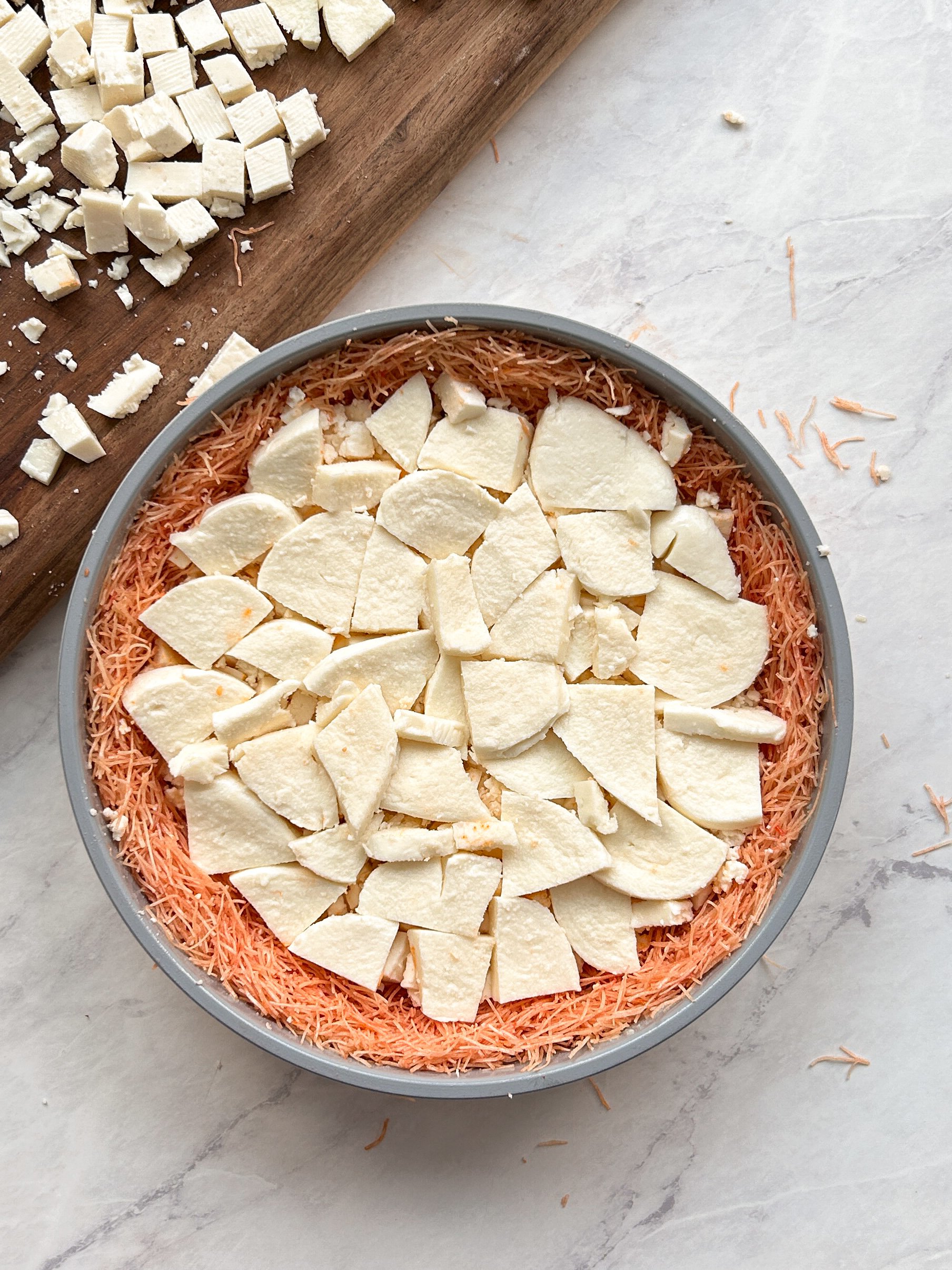 process of layering cheese inside kataifi to make knafeh; mozzarella cheese added