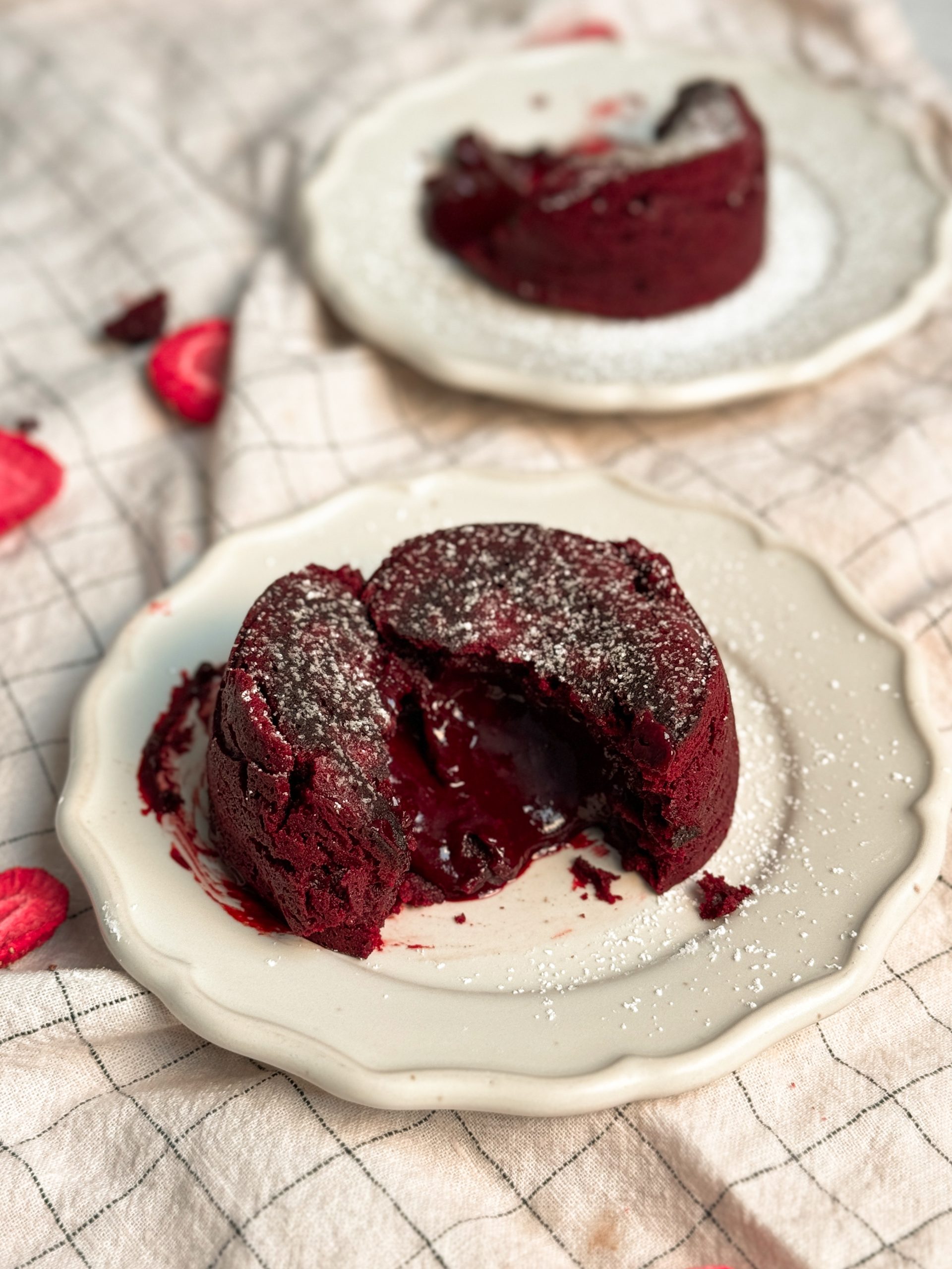 red velvet molten lava cake on a small plate that has been cut into half to let the molten red center ooze out