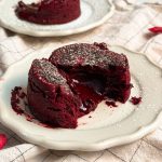 red velvet molten lava cake on a small plate that has been cut into half to let the molten red center ooze out