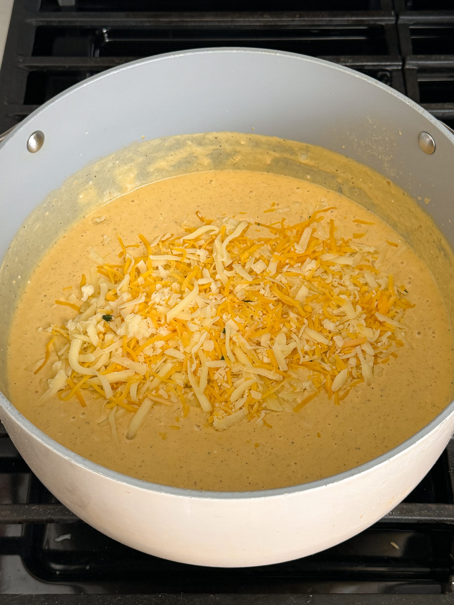 cheese sauce in a saucepan with cheese sprinkled on top